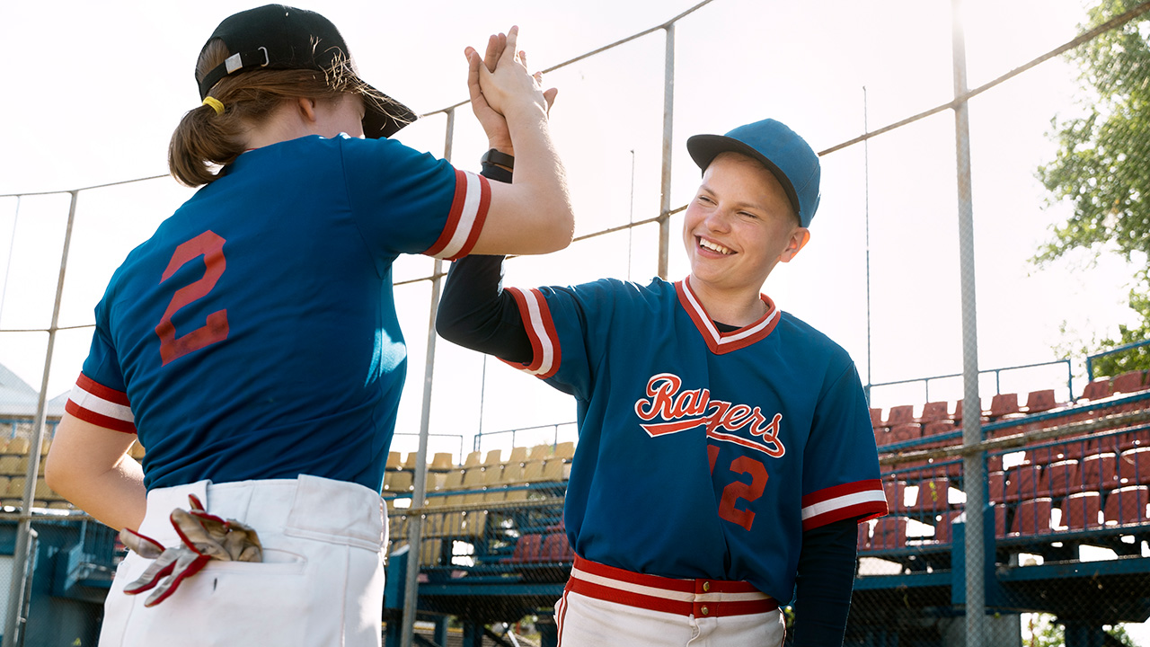 Trusted Coaches insight on how to coach kids. Two youth baseball players high five.